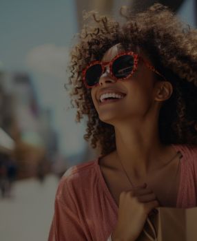 Mulher sorridente com um óculos de sol, aparentemente olhando para algo em seu horizonte